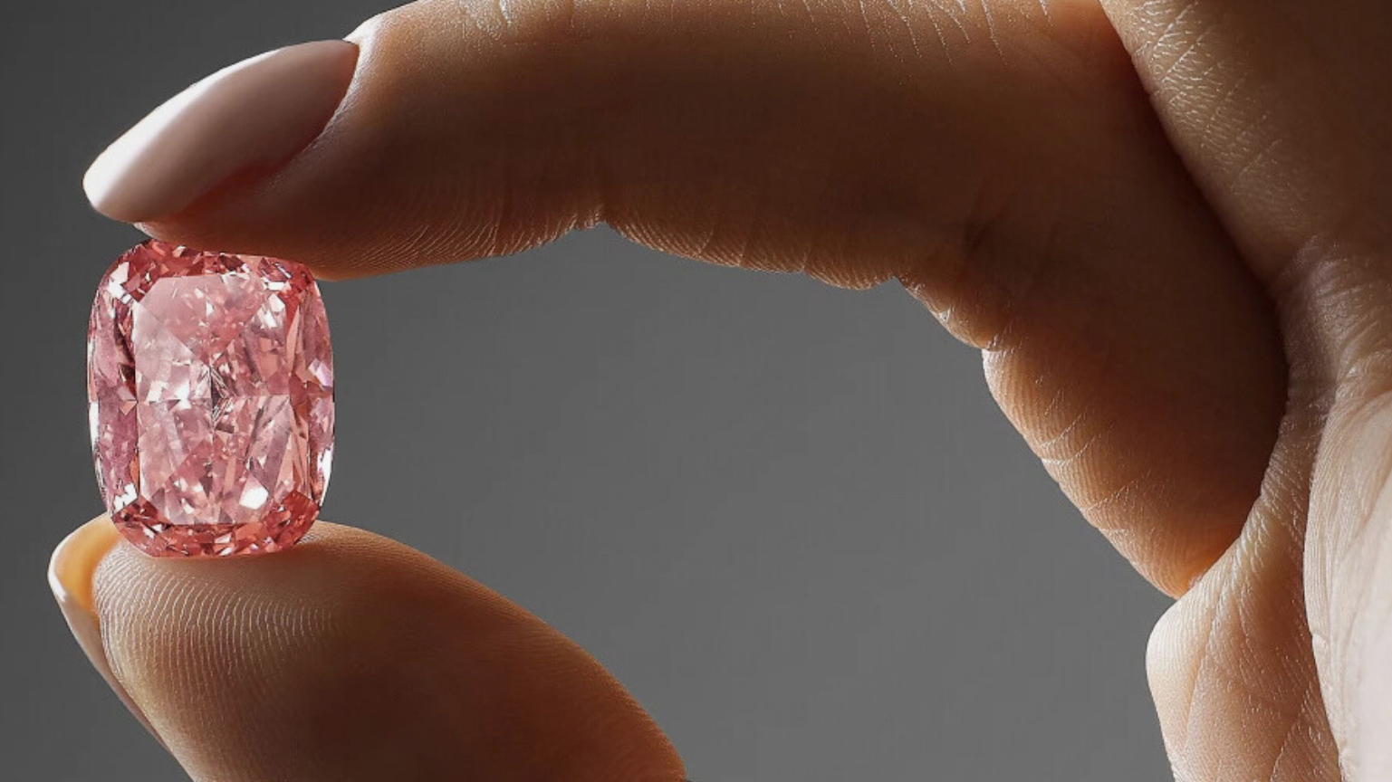 Pinker Diamant gehalten zwischen Daumen und Zeigefinger